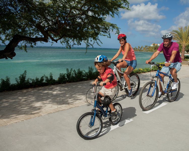 Family riding bikes along oceanside trail.